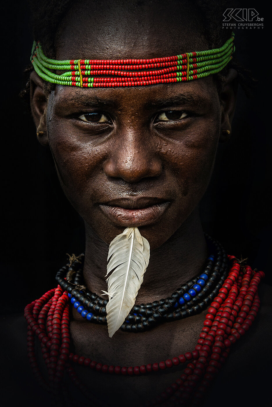 Omorate - Jonge Dassanech vrouw De Dassanech vrouwen zijn vaak uitbundig versierd met kleurrijke hoofdbanden, kralenkettingen en armbanden. Sommigen steken ook een veer door hun kin. Stefan Cruysberghs